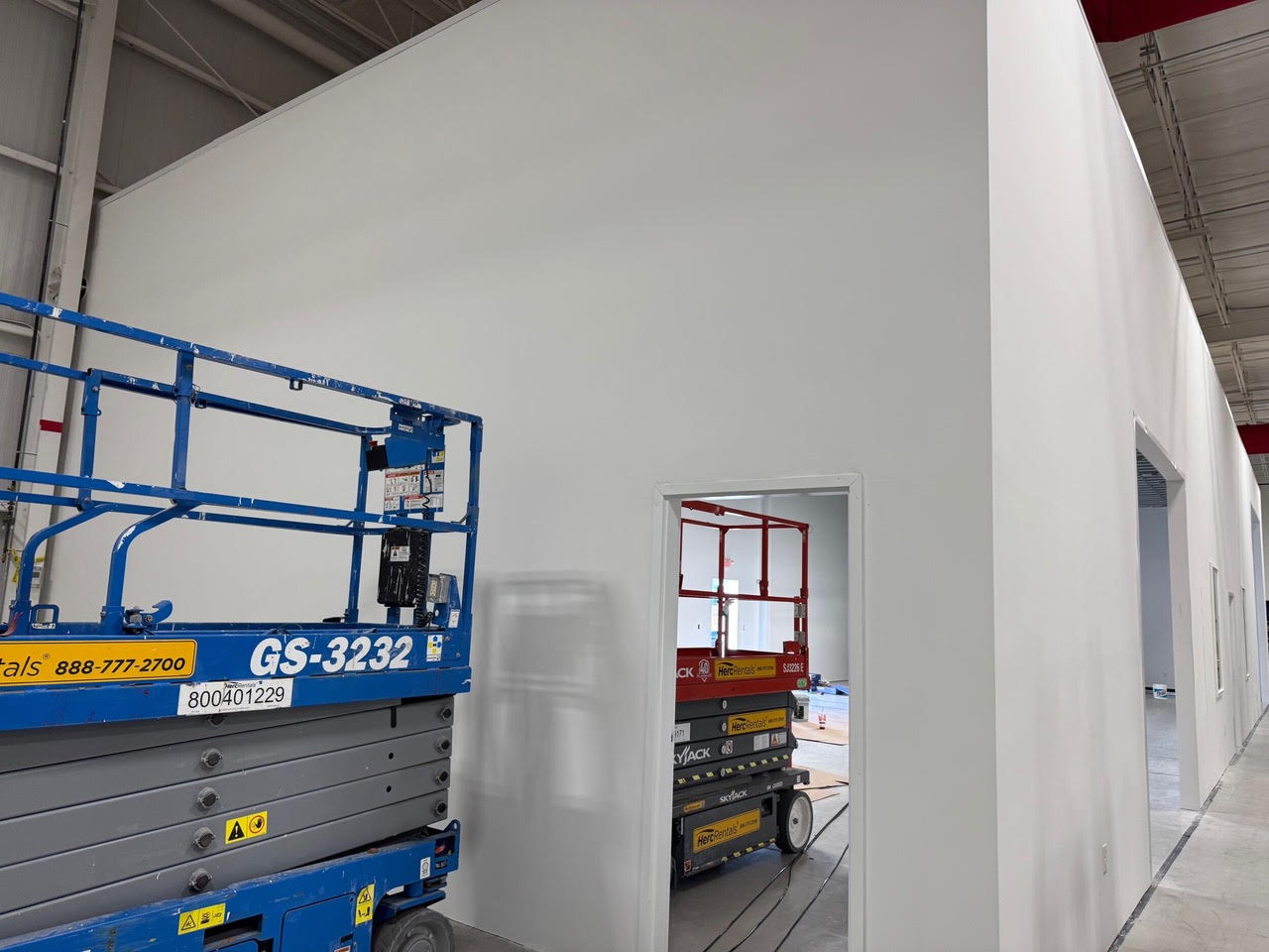 New finished walls and doorways inside the Teknoware warehouse, with scissor lifts in the foreground