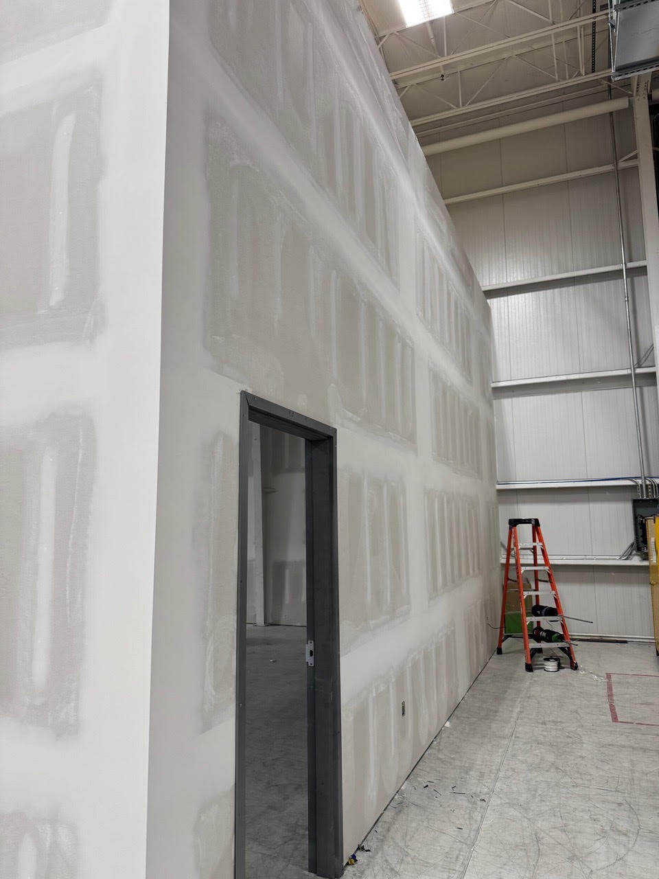 A tall new drywall wall with a doorway, built inside the Teknoware warehouse