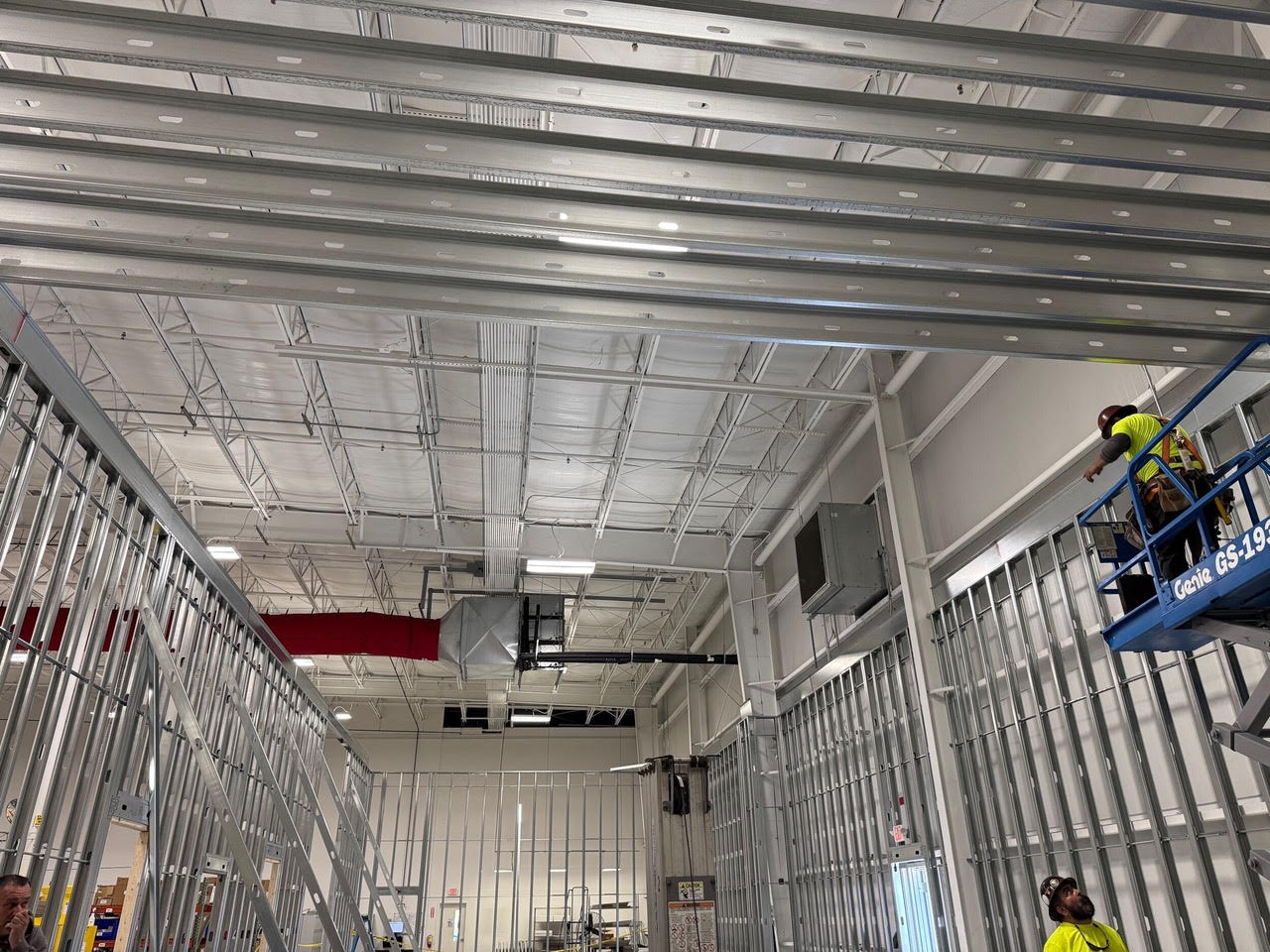 Crew on a lift framing the metal studs and ceiling joists of the new Teknoware space